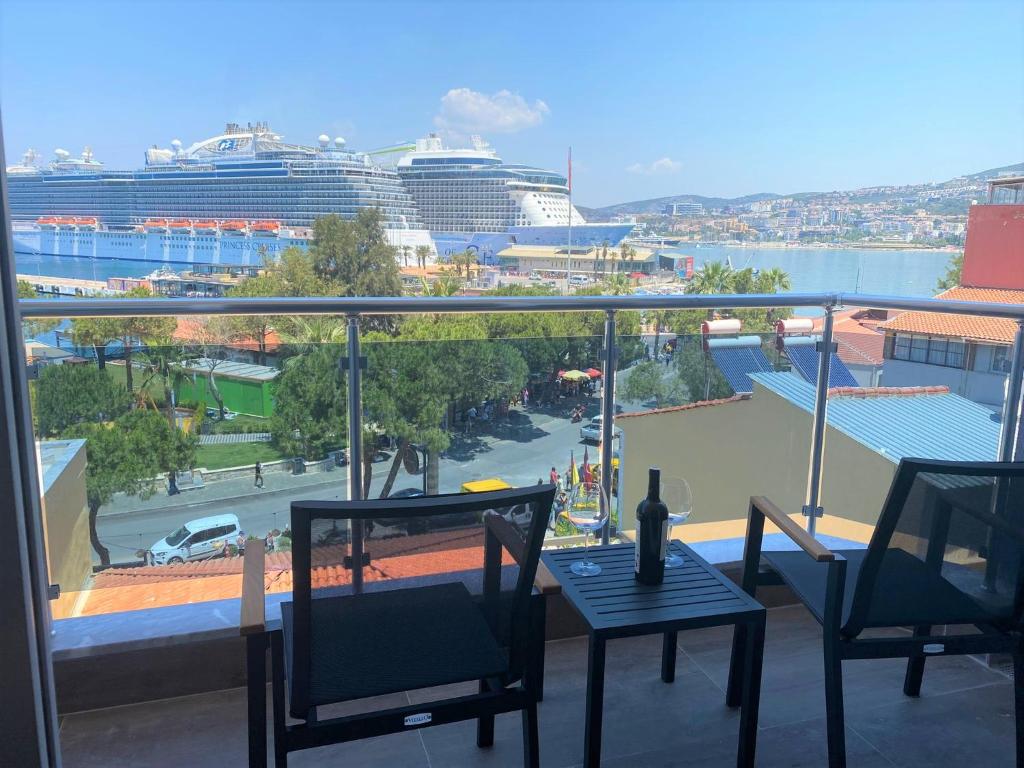 een balkon met een tafel en stoelen en een cruiseschip bij Oksa Apart in Kuşadası