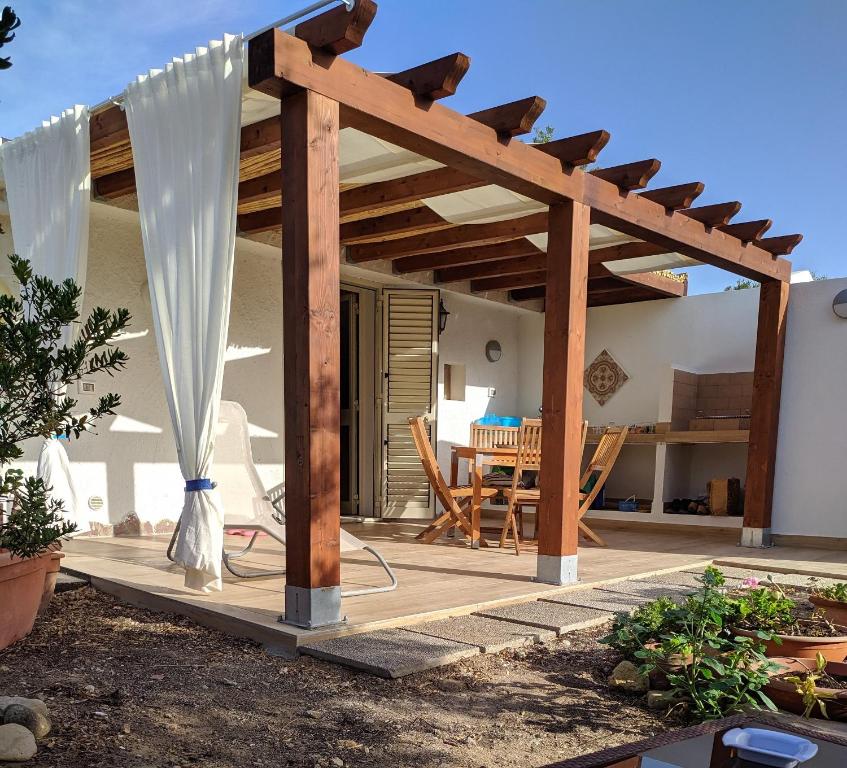 une terrasse avec une pergola en bois et une table dans l'établissement Cottage a 1km dal centro storico, 500 m dal mare,veranda attrezzata, giardino,vista mare, à Carloforte