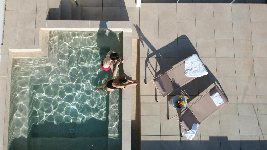 einen Blick über den Pool mit einer Person im Pool in der Unterkunft Casa Romana Hotel Boutique in Sevilla