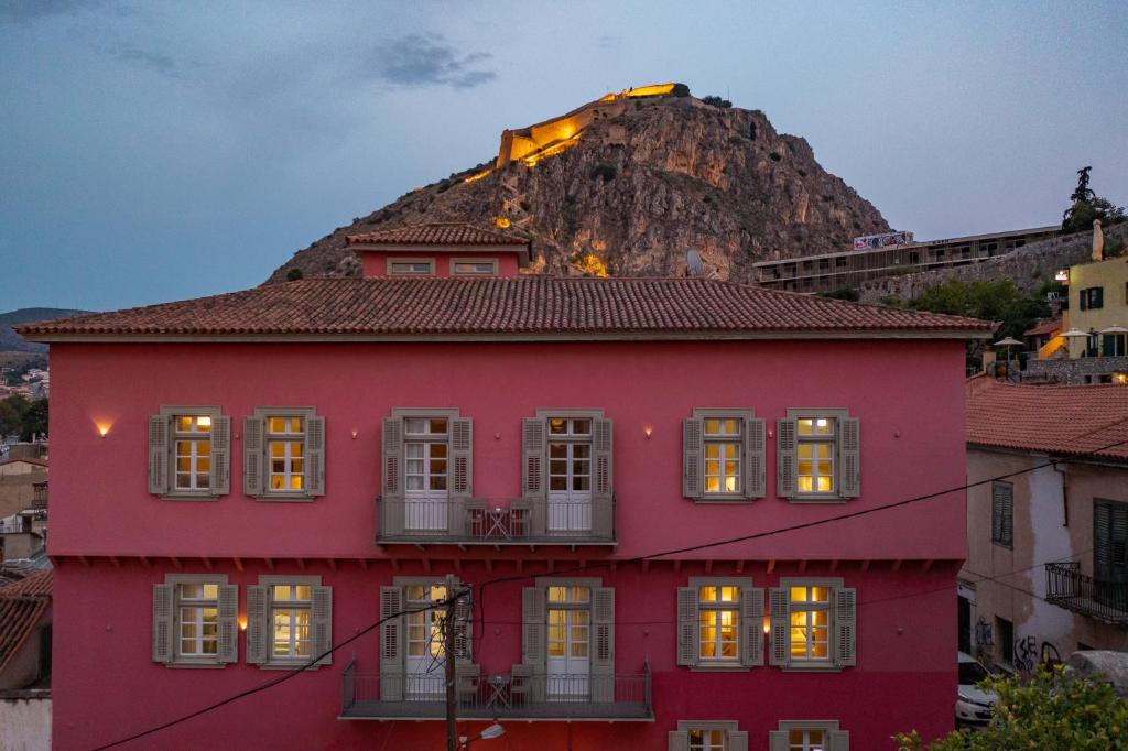 uma casa vermelha com uma montanha ao fundo em Grand Sarai Nafplio em Nafplio