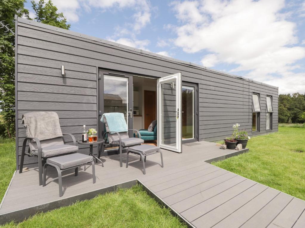 a tiny house with a deck and chairs at Moss of Bourach in Aberlour