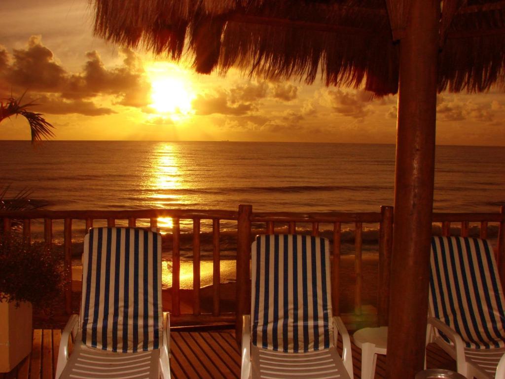 two chairs sitting on a deck watching the sunset at Visual Praia Hotel in Natal