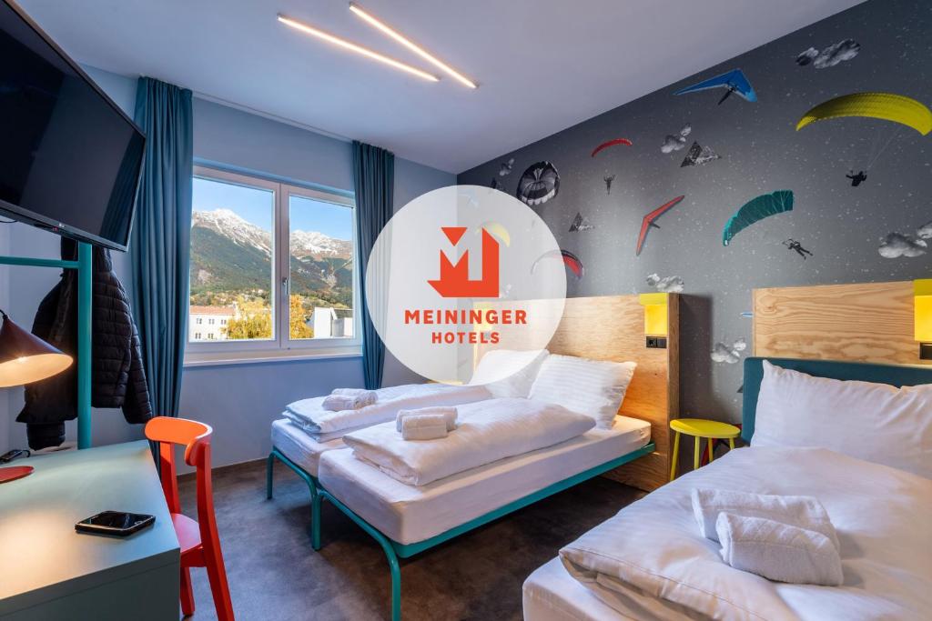 因斯布魯克的住宿－MEININGER Hotel Innsbruck Zentrum，酒店客房设有两张床,墙上有标志