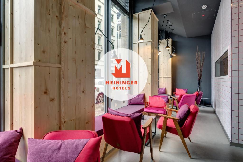 un ristorante con sedie rosa e un cartello che indica l'hotel associato di MEININGER Hotel Leipzig Hauptbahnhof a Lipsia