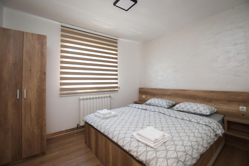 a bedroom with a bed with white sheets and a window at Zanes Apartment in Kladovo