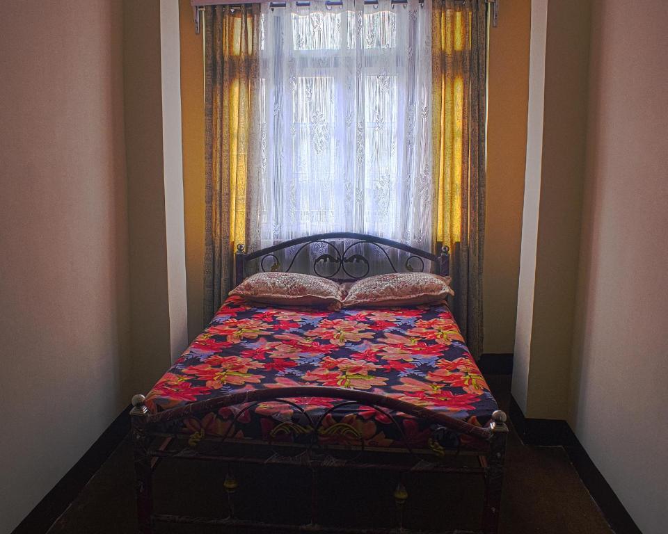 Cama en habitación con ventana en DukeRaj Homestay en Darjeeling