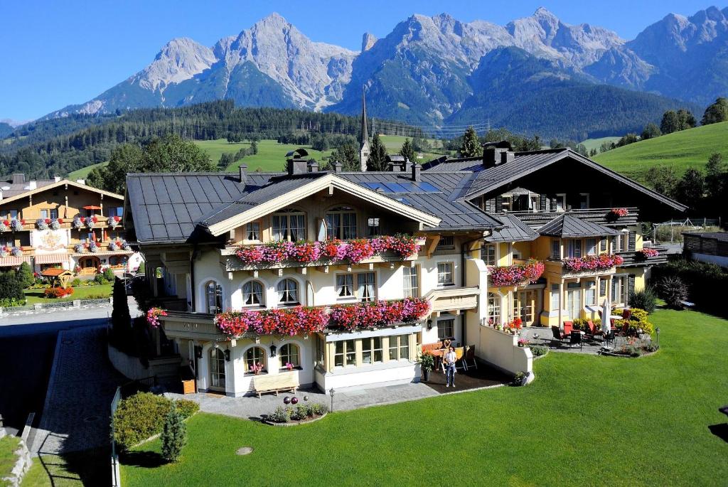 a large house with flowers on the side of it at Appartements-Pension Renberg in Maria Alm am Steinernen Meer