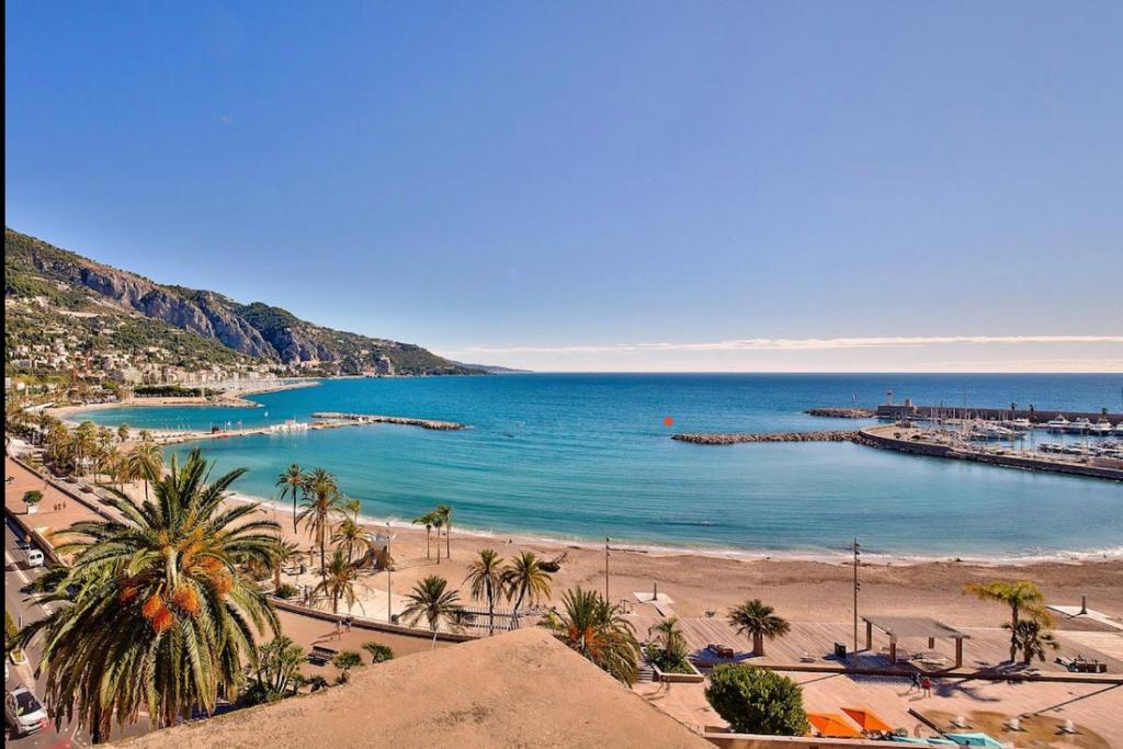 a view of a beach with palm trees and the ocean at Duplex 6 Pers - Panoramic Sea View - Old City - 2 mn Beach in Menton