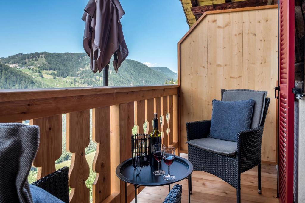 a balcony with two chairs and a table with wine glasses at Ferienwohnung Lavendel Thalerhof in Ponte Nova