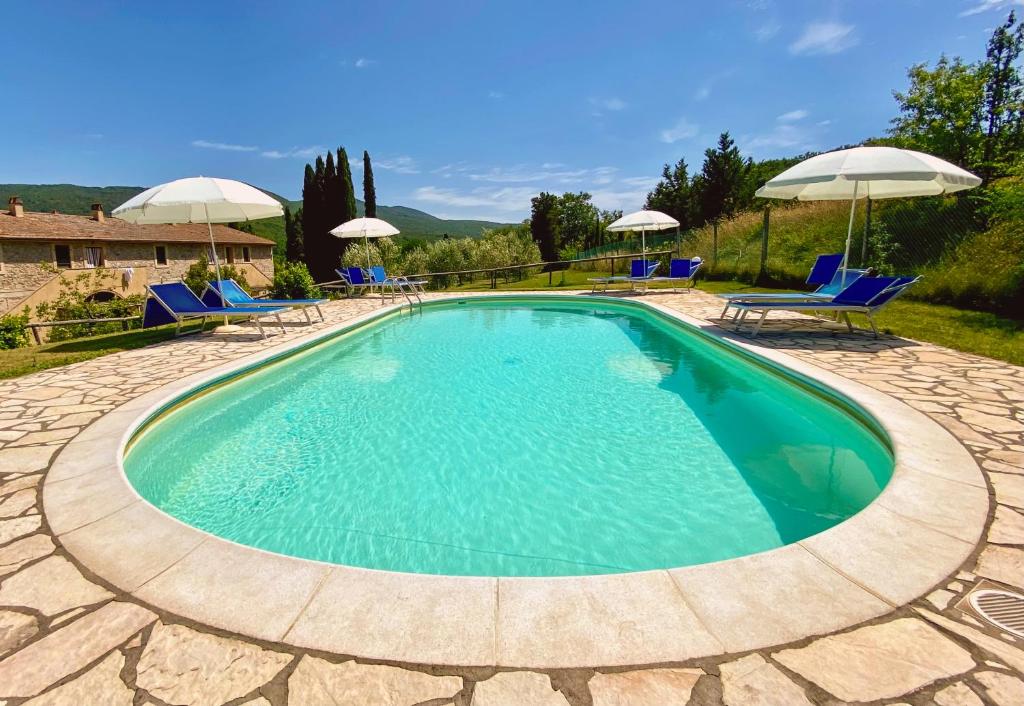 a large swimming pool with chairs and umbrellas at Agriturismo Due Ponti in Chianni