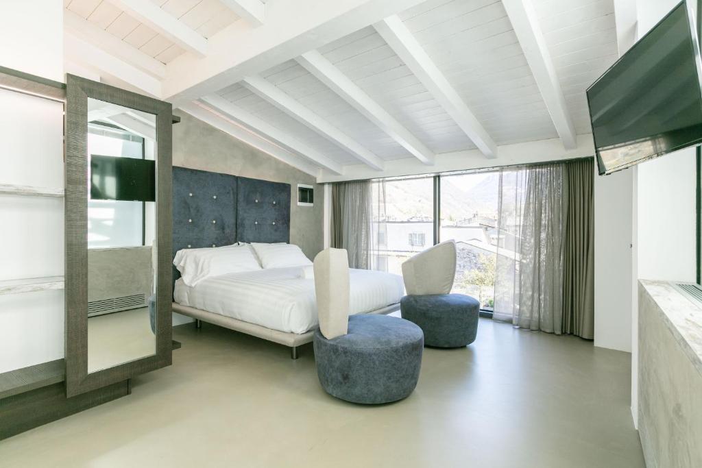 een slaapkamer met een bed en een stoel en een tv bij DOMUS CAVOUR Rooms&Suites in Tirano