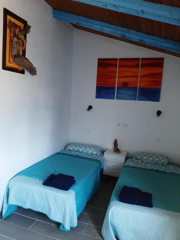 two beds in a room with blue sheets at La Colmena in El Puertecico
