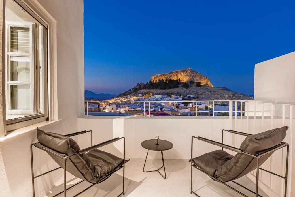 a balcony with two chairs and a table with a view at Peni sol Superior Studios Lindos in Líndos