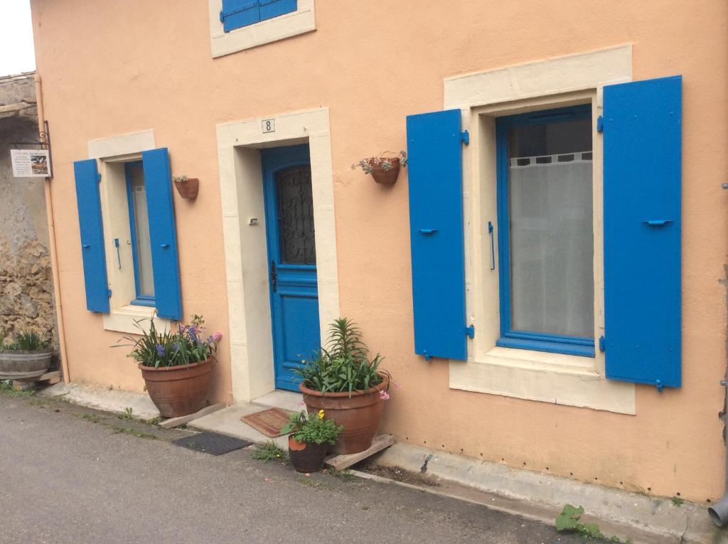 une maison avec portes bleues et plantes en pot à l'extérieur dans l'établissement La Maison des Remparts, à Saint-Jean-de-Barrou