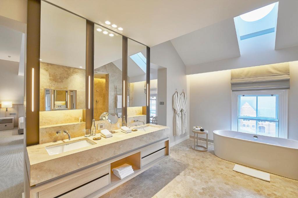 a bathroom with two sinks and a tub and a large mirror at COMO The Treasury in Perth