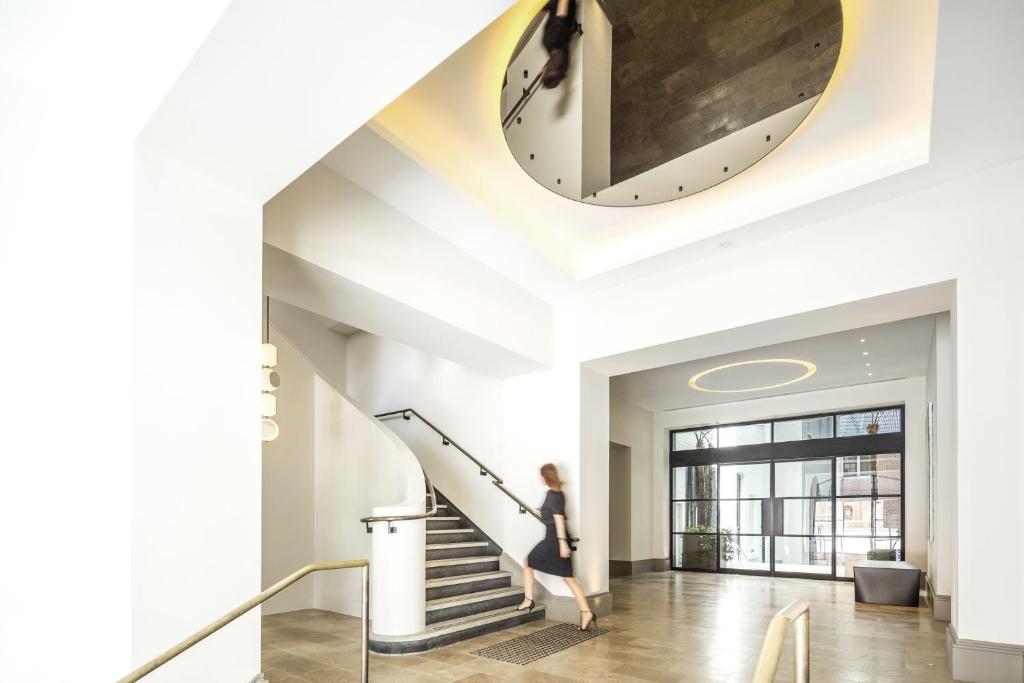 a woman walking down a staircase with a large clock on the ceiling at COMO The Treasury in Perth