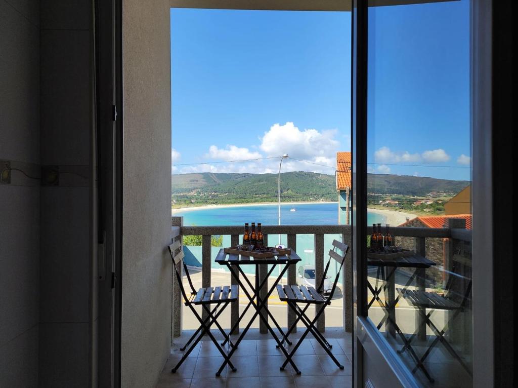 a balcony with a table and chairs and a view of the ocean at Apartamento AREAL in Fisterra