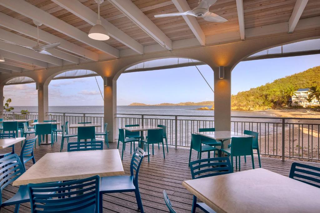 ein Restaurant mit Tischen und Stühlen und Meerblick in der Unterkunft Limetree Beach Resort by Club Wyndham in Raphune