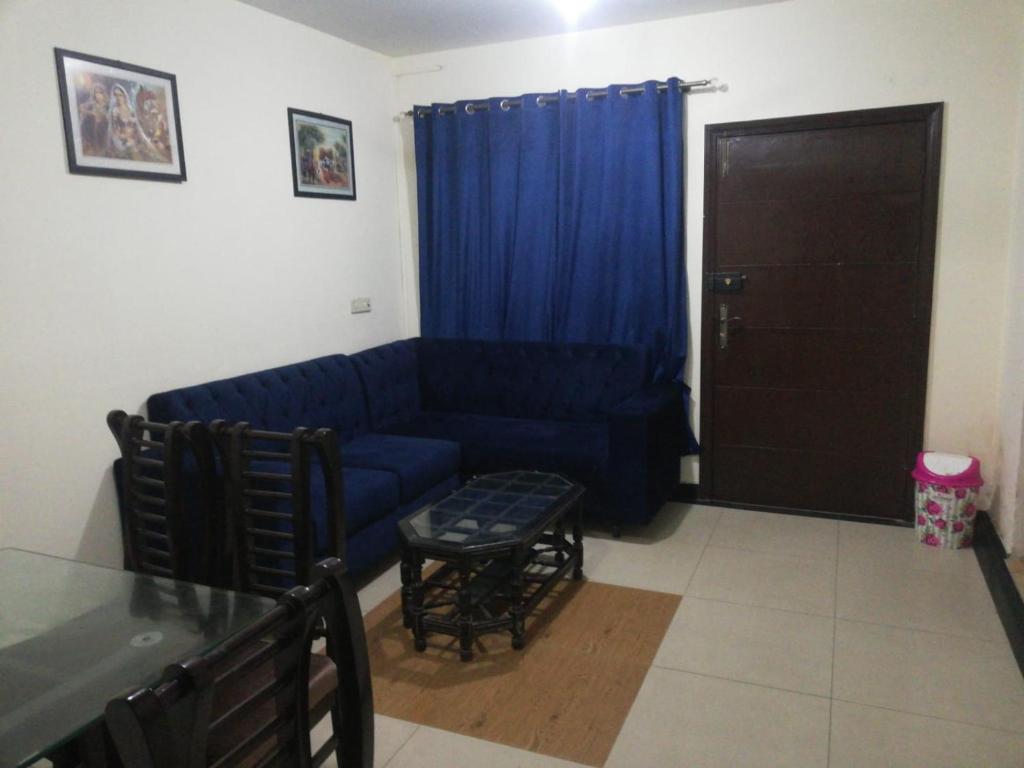uma sala de estar com um sofá azul e uma mesa em Lovely 1-Bedroom Apartment em Lahore