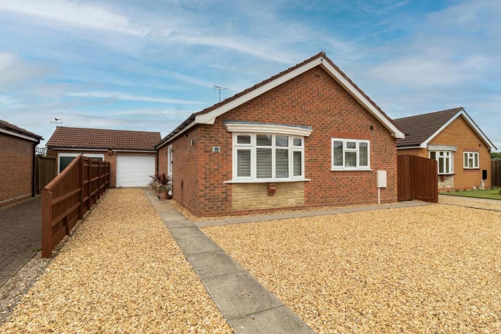 a brick house with a fence and a driveway at Cedar Drive, Holbeach - 1 to 4 - Self Catering in Holbeach