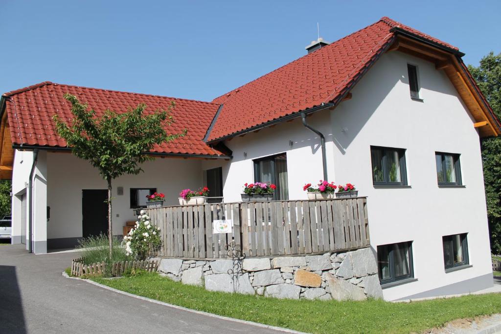 ein weißes Haus mit einem Zaun und einem roten Dach in der Unterkunft Desl´s little farm in Waldburg