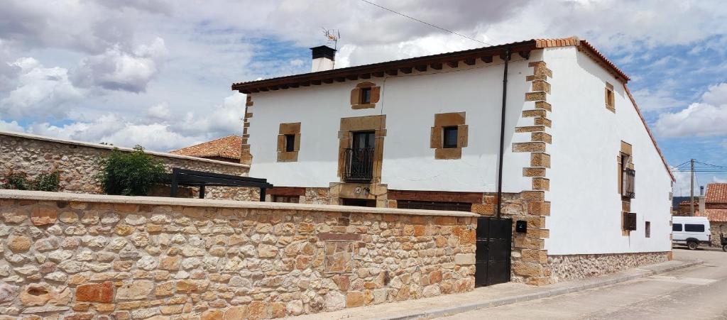 a white building with a stone wall next to at Casa del Medio in Fuentecantos