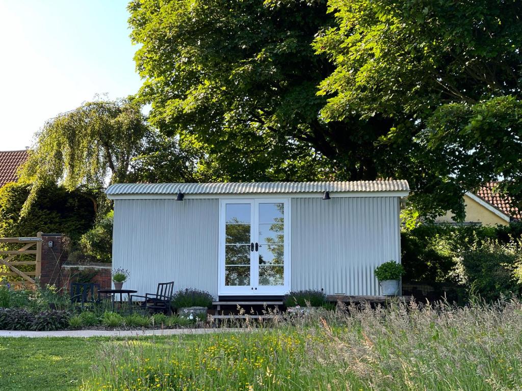 a small white shed with a bench in a yard at Self-catering shepherds hut with private garden in Durhams idyllic countryside in Durham