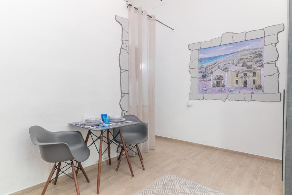 a table and two chairs in a room with a painting at Quercus Ilex B in Arzachena