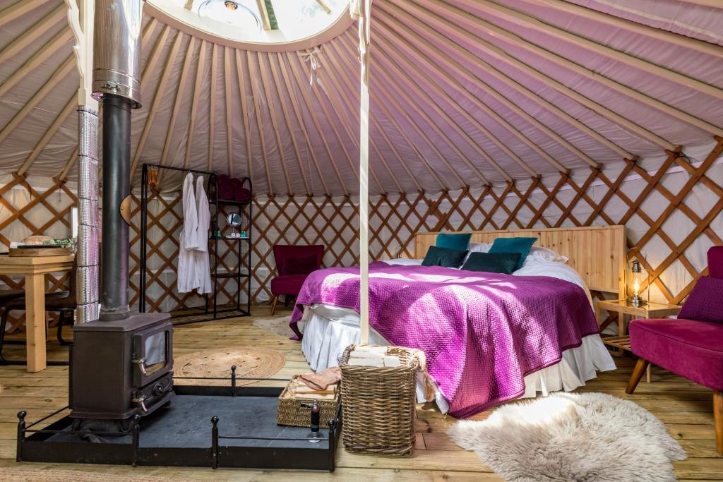 a bedroom with a bed and a stove in a yurt at Luxury Yurt with Hot Tub - pre-heated for your arrival in Buxton