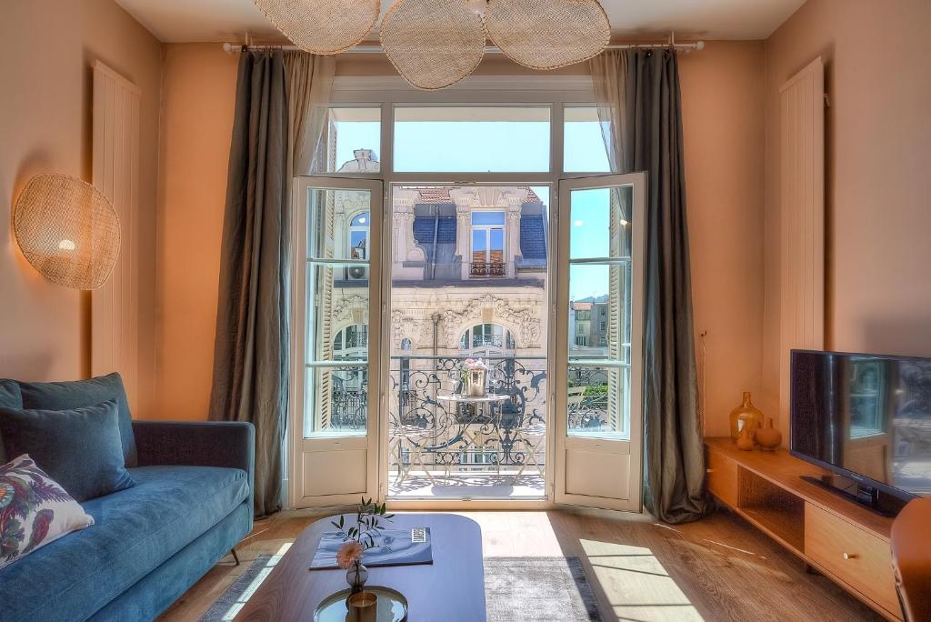 sala de estar con sofá azul y ventana grande en Maison Lamartine - Nice, en Niza