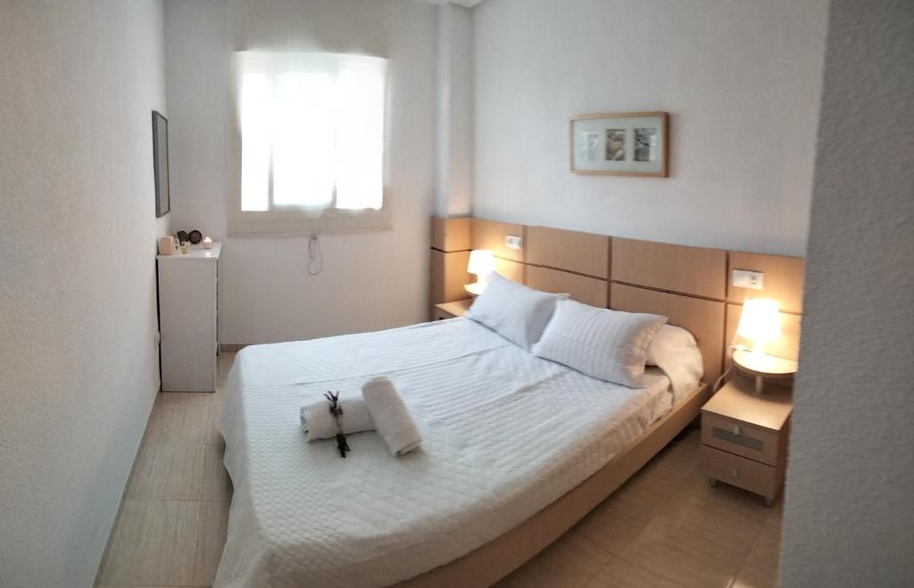 ein Schlafzimmer mit einem weißen Bett mit einem Kreuz darauf in der Unterkunft Confort y Relax in Oropesa del Mar
