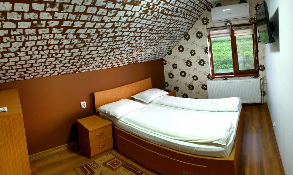 a small bedroom with a bed and a window at Cabana LaGică in Beclean