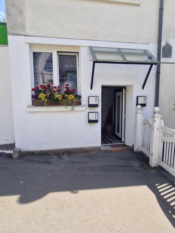 a white house with a window with flowers in a window box at Ferienwohnung Wunderlich rot in Münchberg