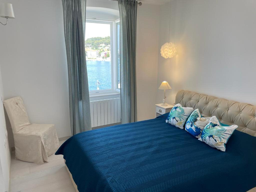 a bedroom with a blue bed with a chair and a window at Apartman Priko 63A in Mali Lošinj