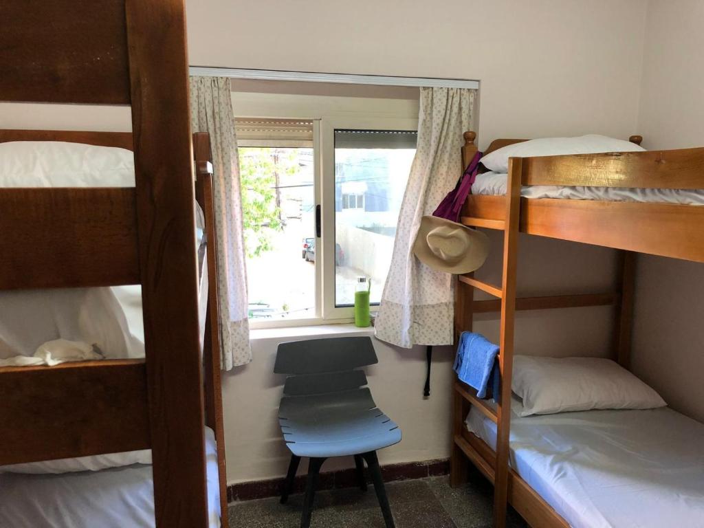 a bedroom with bunk beds and a chair and a window at Sina Hostel in Tirana