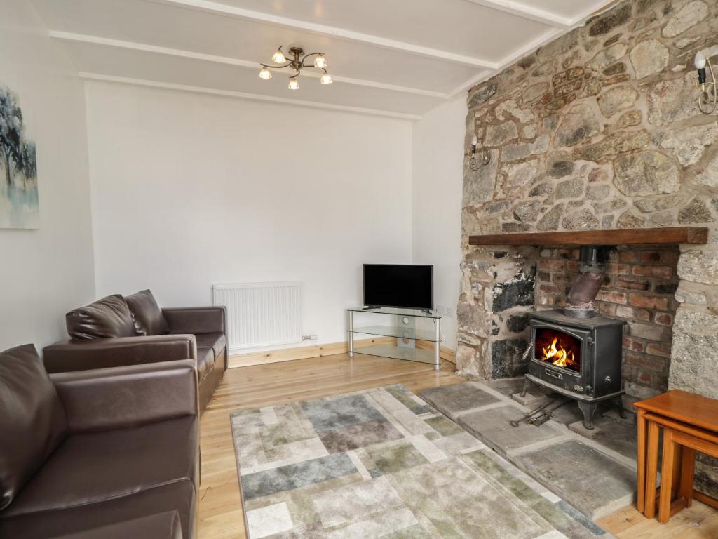 a living room with a couch and a fireplace at Shaw Cottage in Dumfries