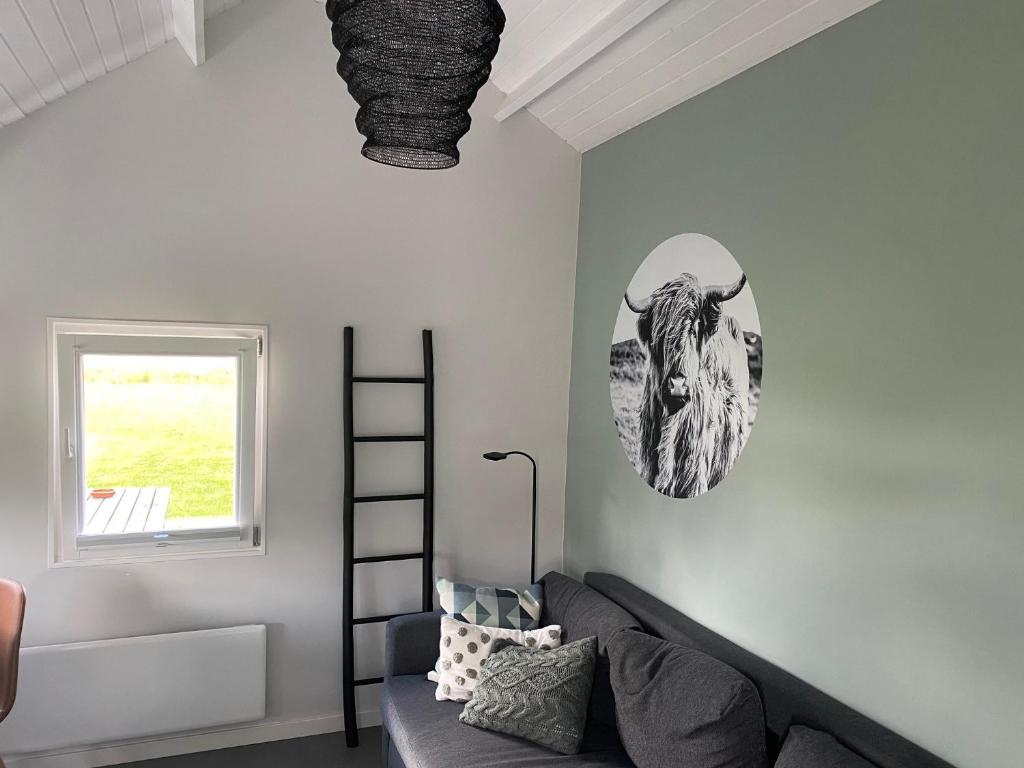 una sala de estar con sofá y una foto de un toro en la pared en Blokhut Klein Meerzicht en Haren