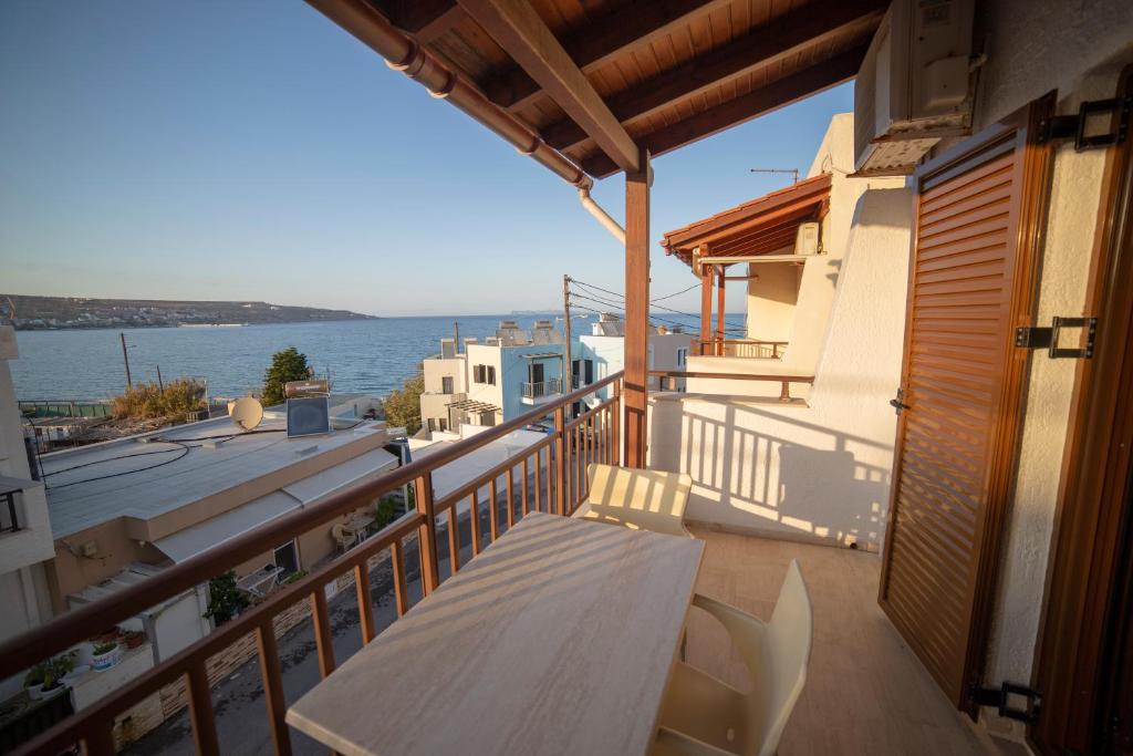 een balkon met een tafel en uitzicht op het water bij Bay View Apts II in Sitia