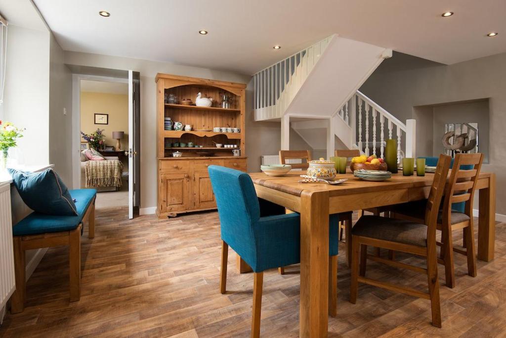 a dining room with a wooden table and blue chairs at Pirnie Cottage in Kelso