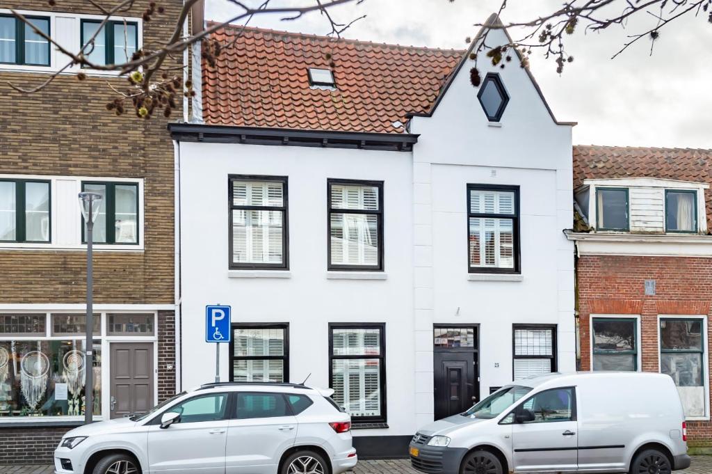 twee auto's geparkeerd voor een wit huis bij Unieke stadswoning met jacuzzi en sauna max 8 pers in Goes