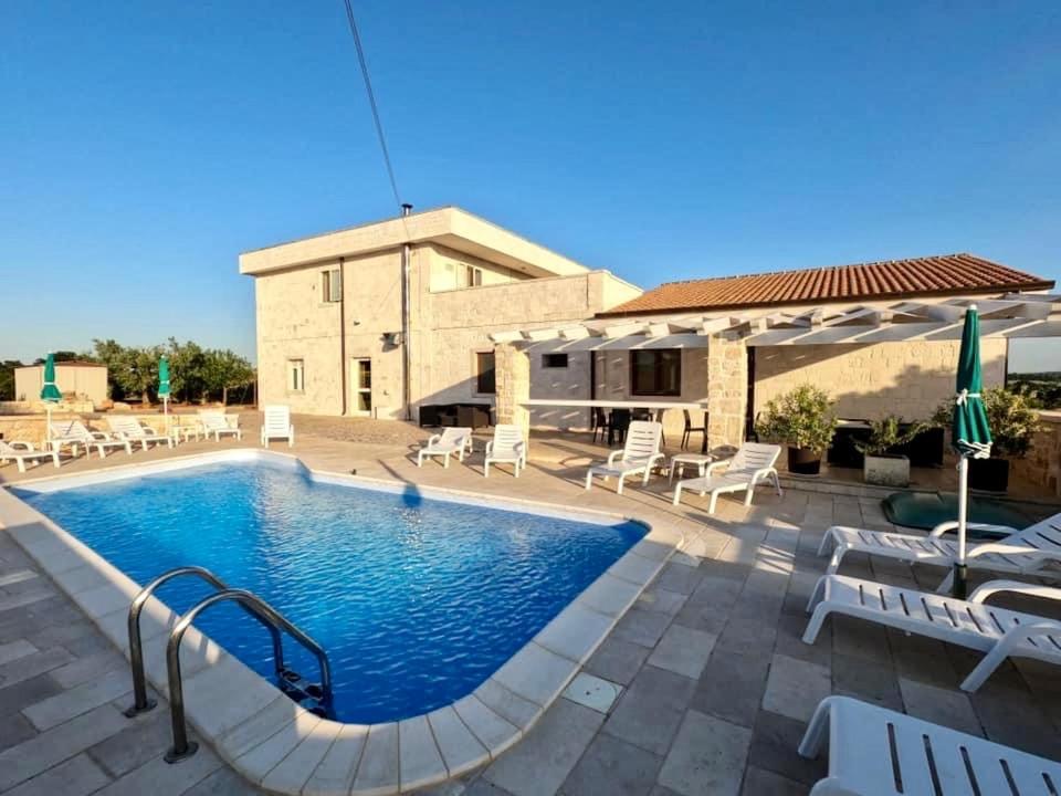 una piscina con sedie e ombrelloni accanto a un edificio di B&B Il Leccio ad Alberobello