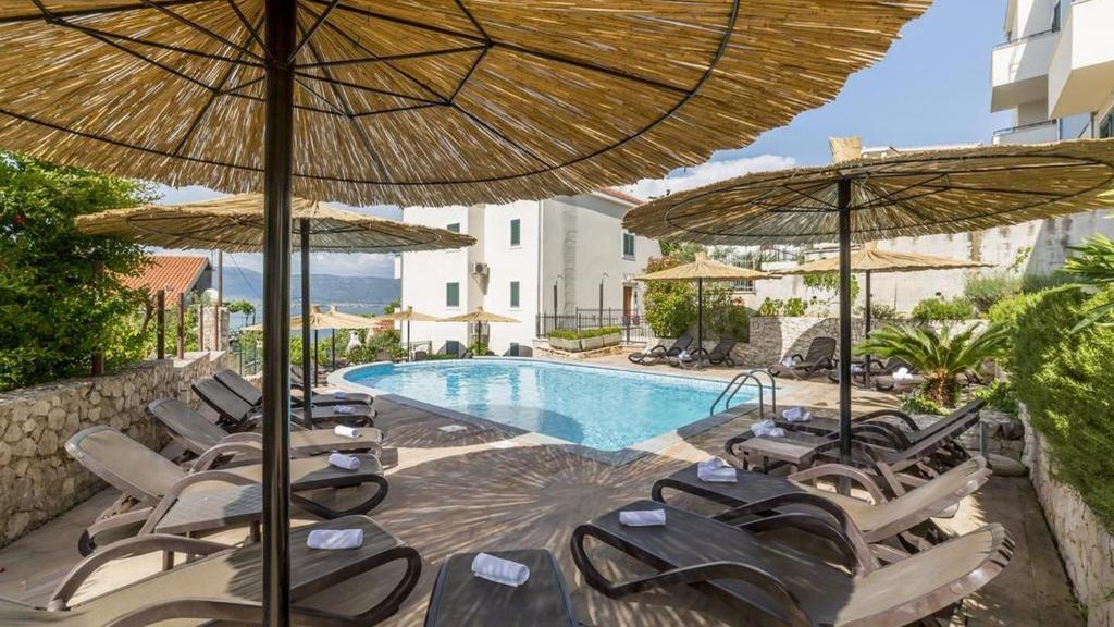 a group of chairs and umbrellas next to a pool at Apartment Clementin in Slatine