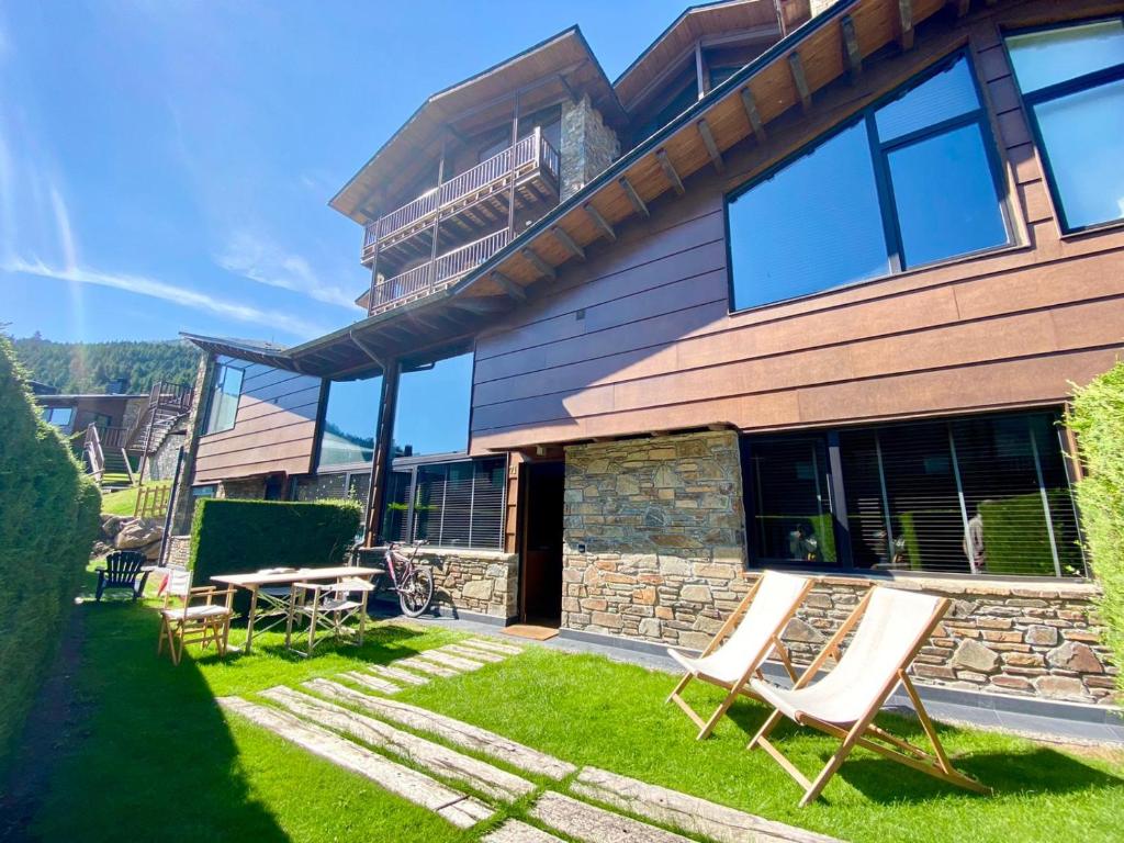 una casa con un patio con sillas y un edificio en Apartament Pla de Masella, en Alp