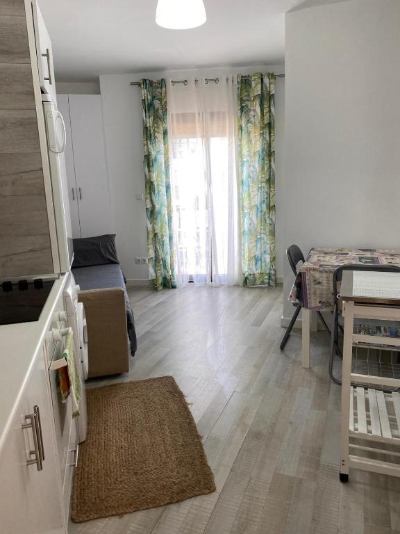ein Wohnzimmer mit einem Bett, einem Tisch und einem Fenster in der Unterkunft Estudio sin habitación ,todo en una estancia Blanco Denia in Denia