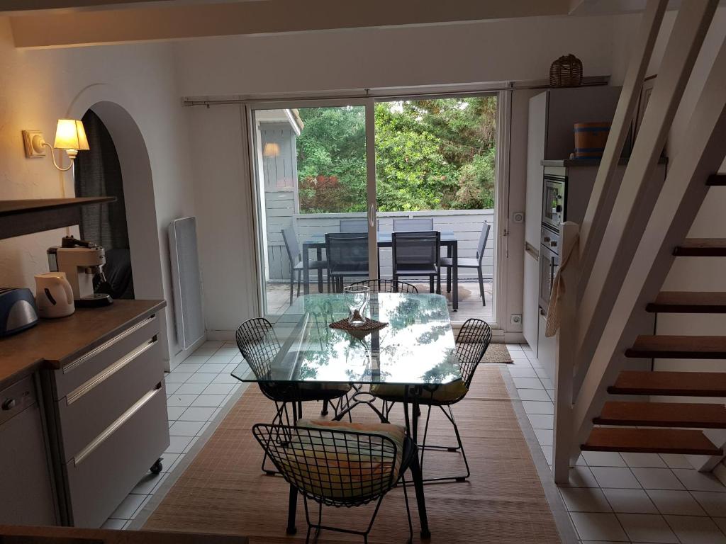 uma cozinha com uma mesa de vidro e cadeiras num pátio em A 100m de la plage, Aperçu mer, wifi, 2 chambres, 2 salles de bains, 2WC em Saint-Georges-de-Didonne