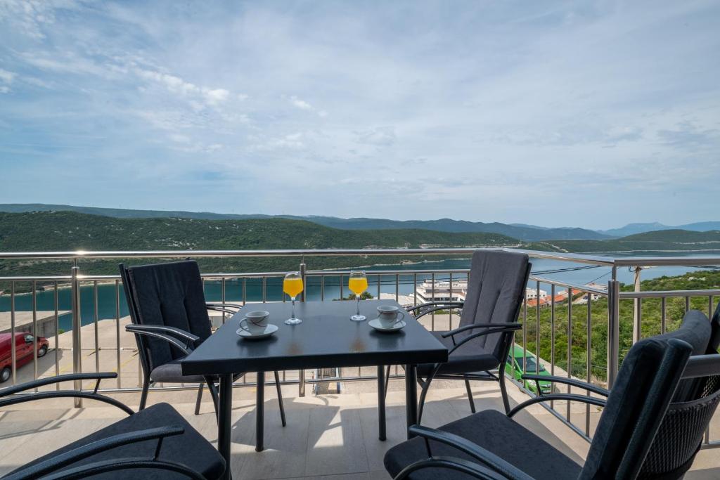een tafel en stoelen op een balkon met uitzicht op het water bij Apartments Glorija in Neum