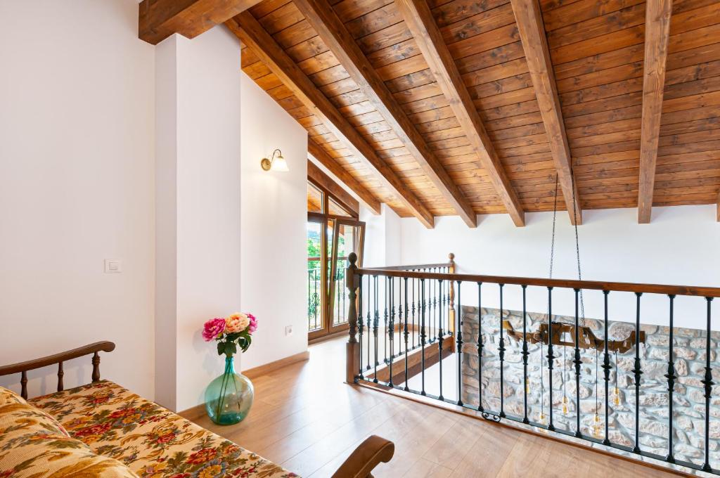 a room with a bed and a vase with flowers in it at La casita de susa en mazcuerras in Villanueva de la Peña