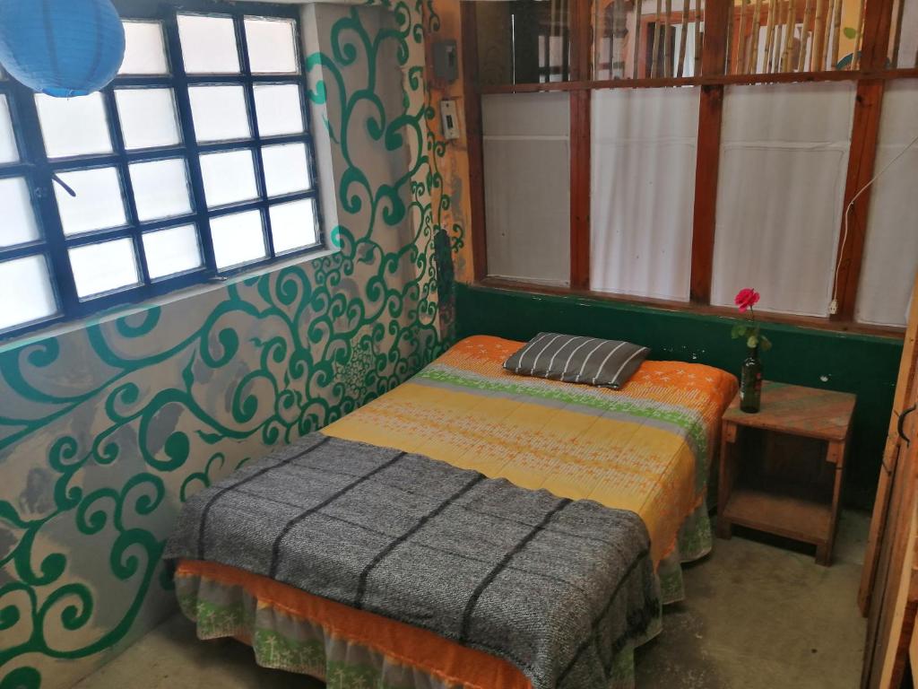 Cama pequeña en habitación con ventanas en Casa Kasa Hostel, en San Cristóbal de Las Casas