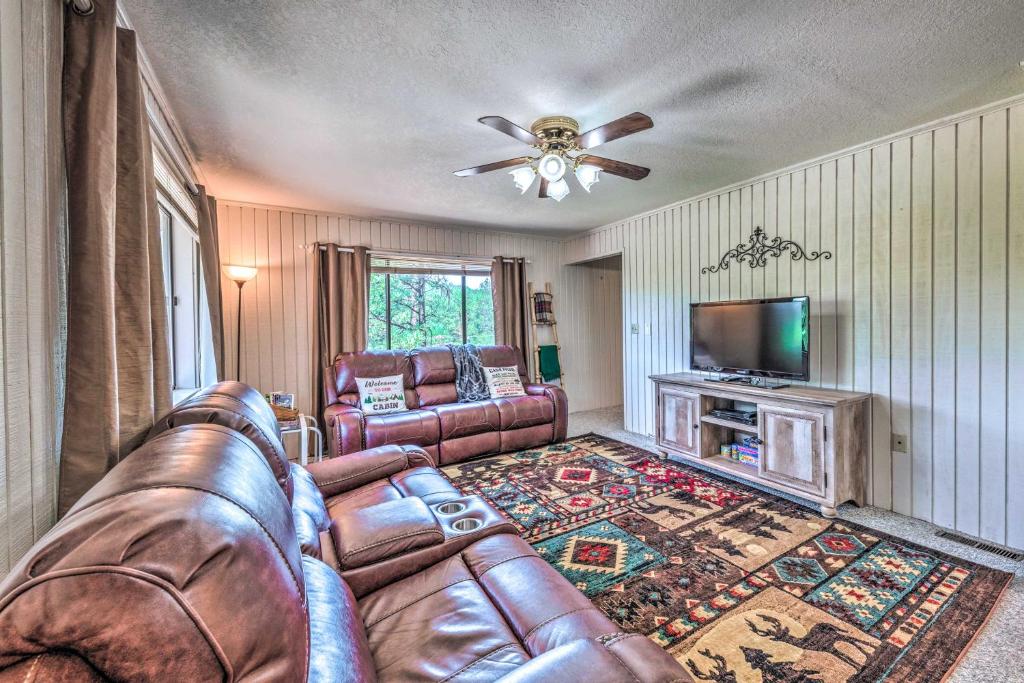 a living room with a leather couch and a flat screen tv at Relaxing Ruidoso Getaway with Spacious Deck! in Ruidoso