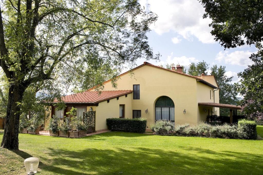 una casa con un césped verde delante de ella en Agriturismo Petrognano, en SantʼEllero